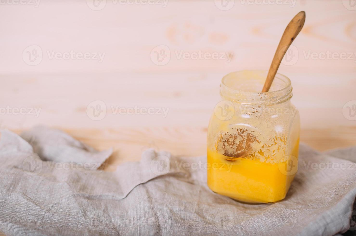 um pote de mel sólido e pano em fundo de madeira. foto