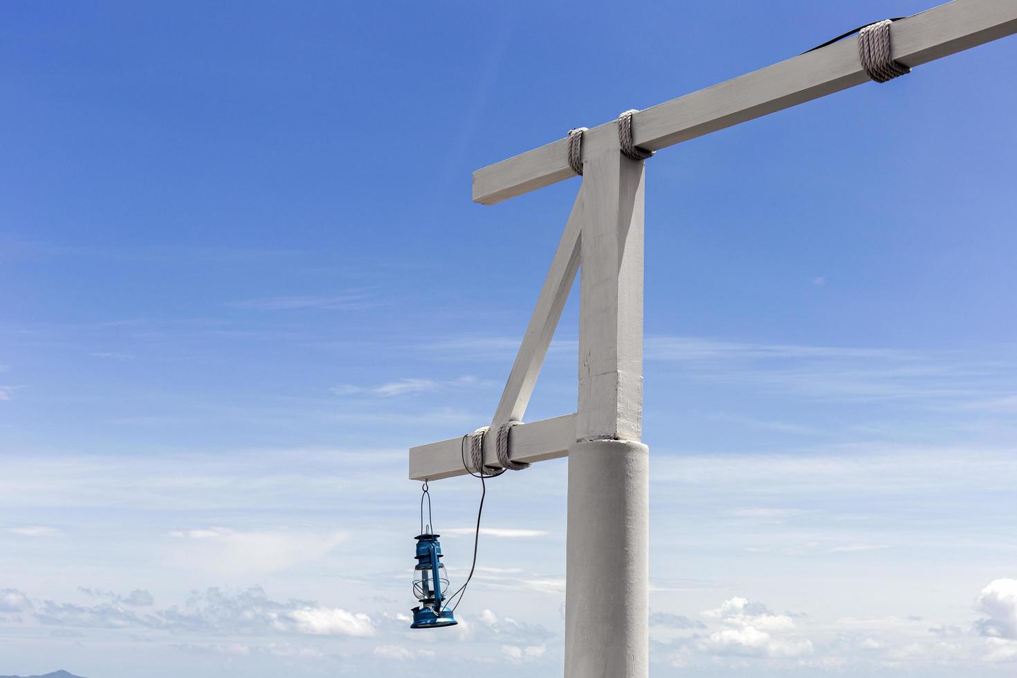 poste de madeira branco com lanternas penduradas em um fundo de céu brilhante. foto