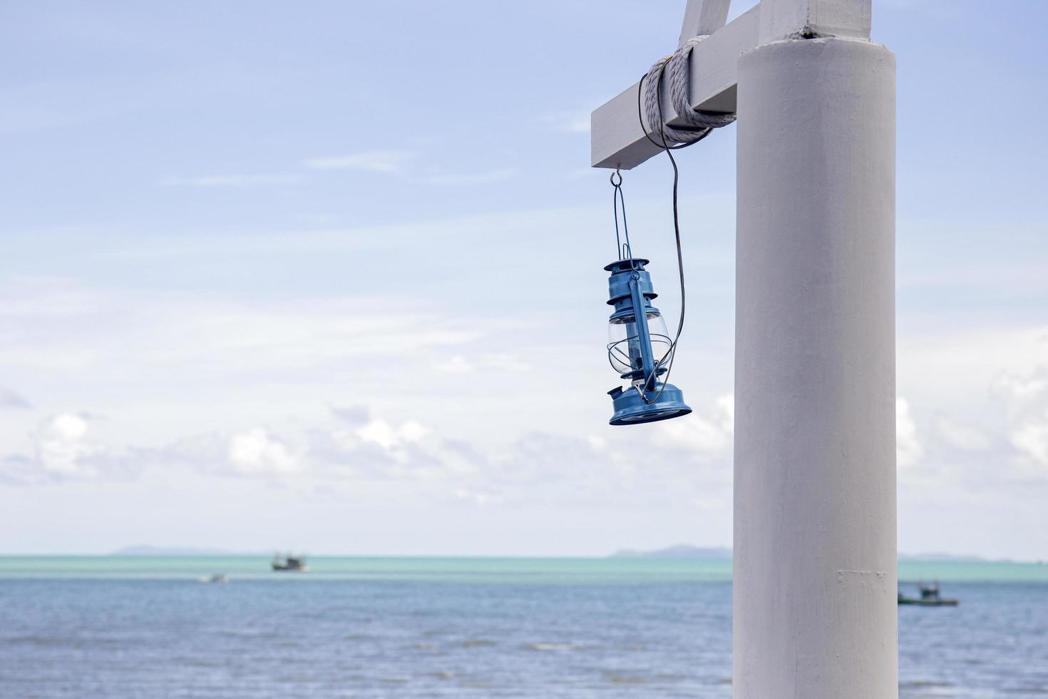 lanternas azuis em postes de madeira brancos atrás de uma vista para o mar de um dia brilhante. foto
