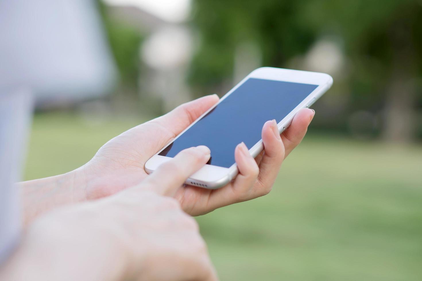 mãos de mulher com smartphone no jardim foto