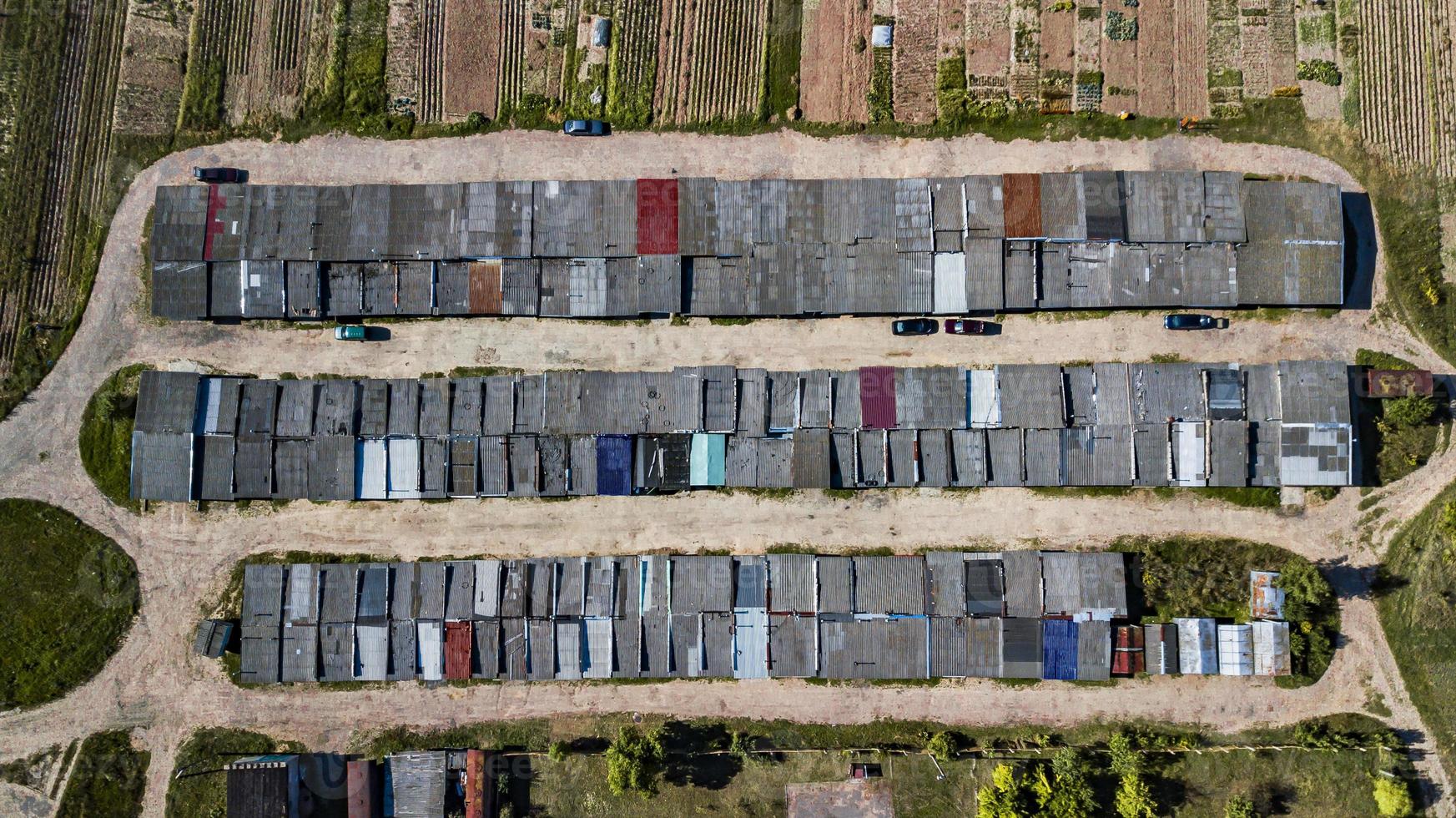 vista aérea da garagem do apartamento com estacionamento coberto, carros e árvores verdes de prédio residencial de vários andares no início da manhã. infraestrutura urbana e conceito de transporte. vista panorâmica. foto