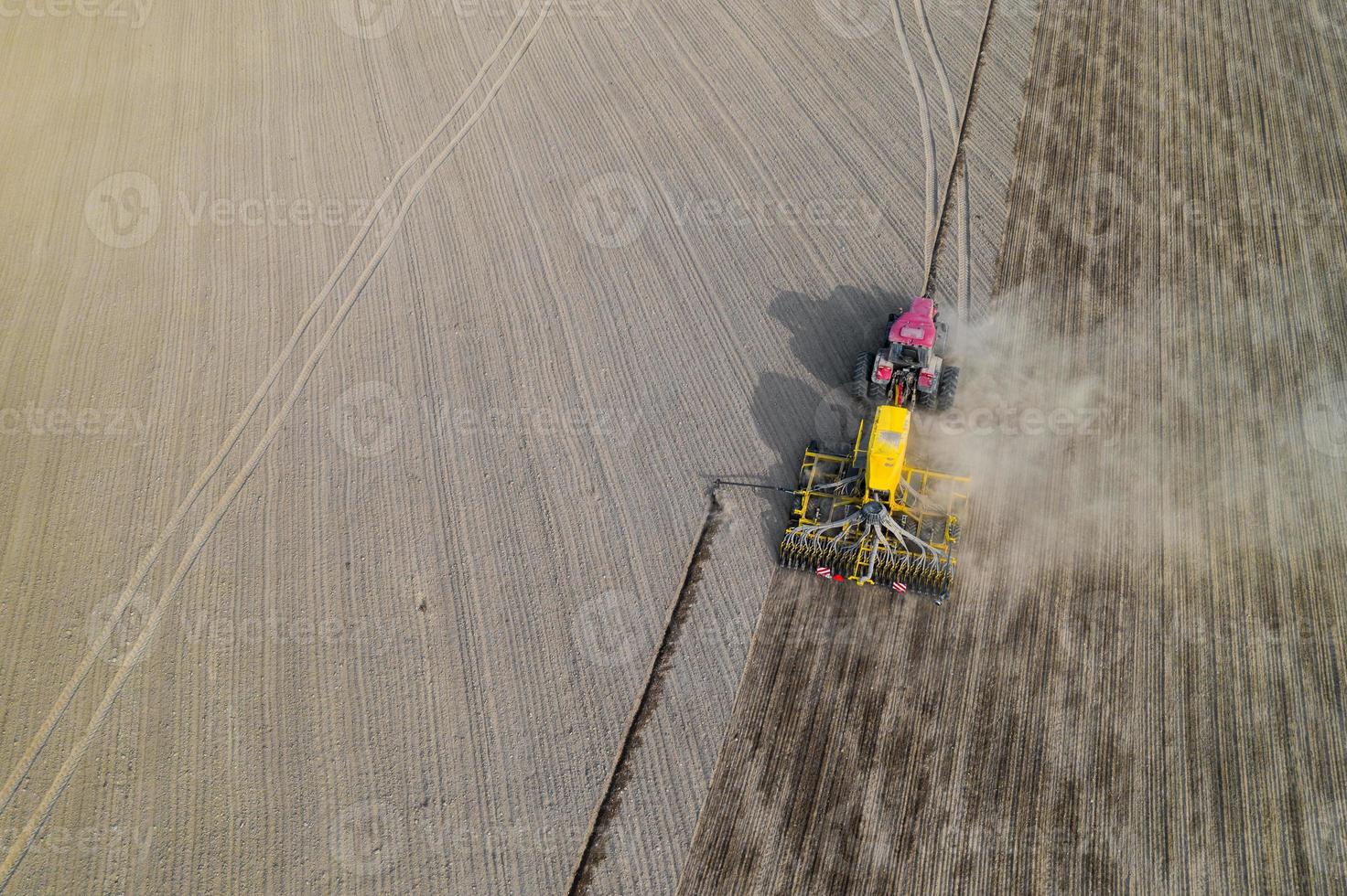 trator em um campo arado, vista superior. campo agrícola para plantar legumes. trator faz sulcos no campo. foto