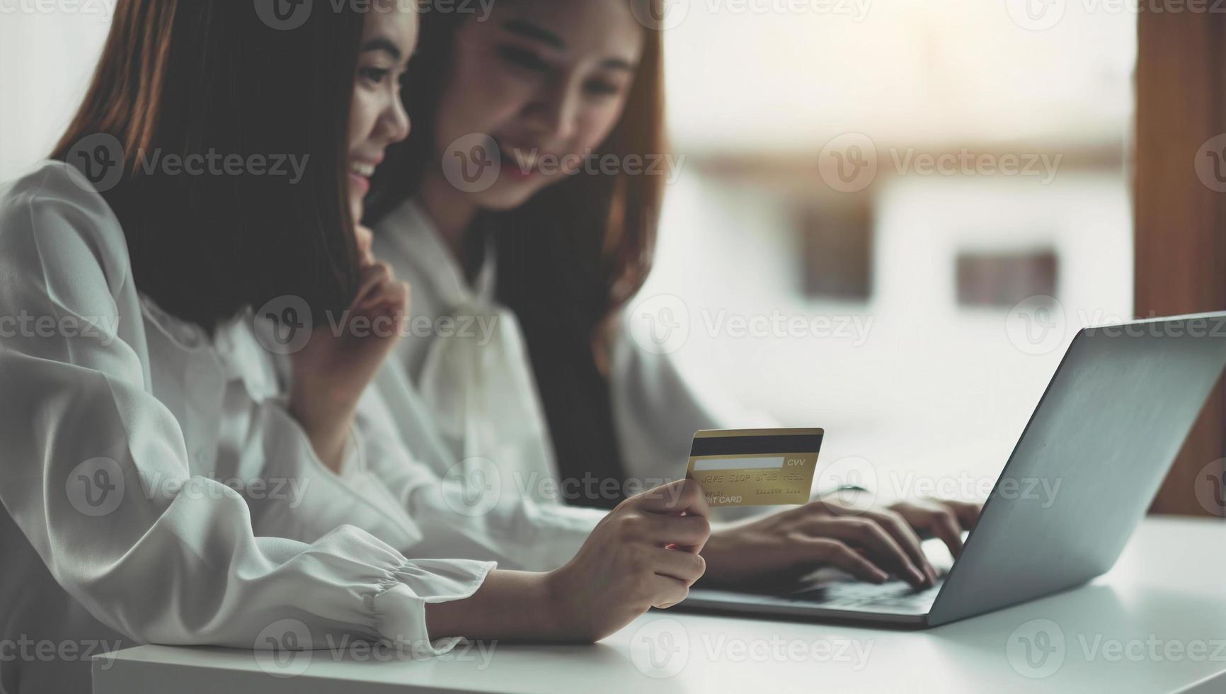 duas jovens mulheres asiáticas segurando cartão de crédito e usando computador portátil para fazer compras on-line com o conceito de felicidade, negócios e tecnologia, marketing digital, estilo de vida casual foto