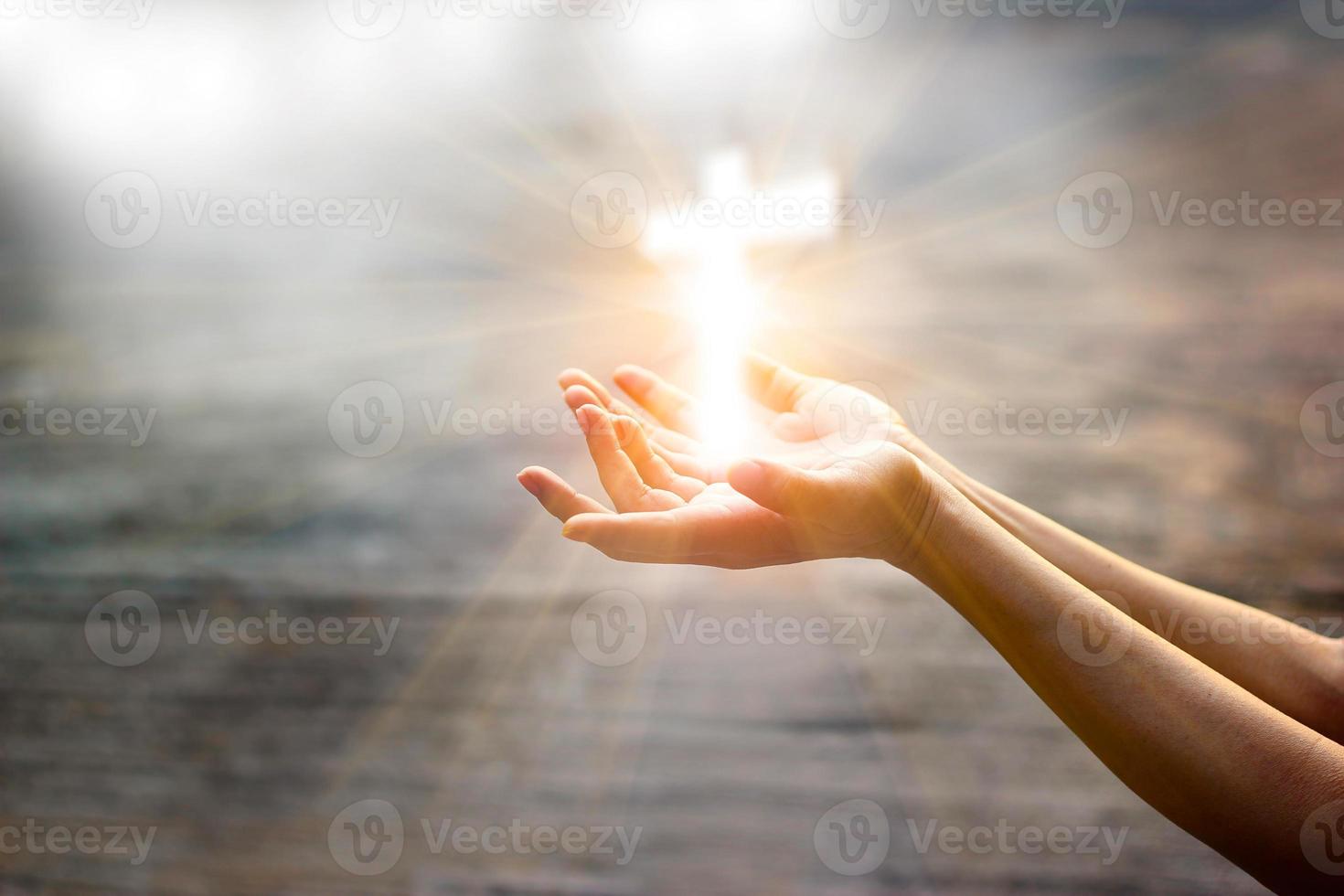 mulher com cruz branca nas mãos rezando por bênção de Deus sobre fundo de luz solar, conceito de esperança foto
