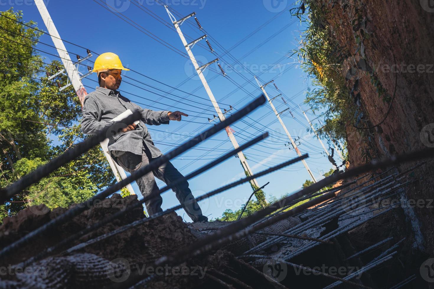 arquiteto ou engenheiro civil com capacete no canteiro de obras, verificando o cronograma no computador tablet foto