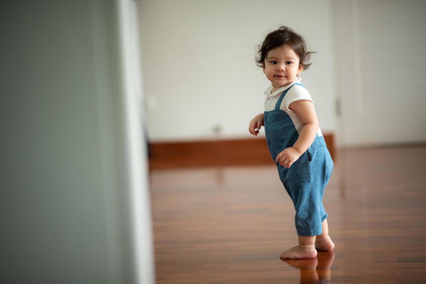 criança bonitinha conceito de família criança, bebê aprendendo a andar com pai e mãe para ajudar a cuidar e segurar a mão, primeiro passo com apoio dos pais na infância, pequeno retrato de amor menino em casa foto