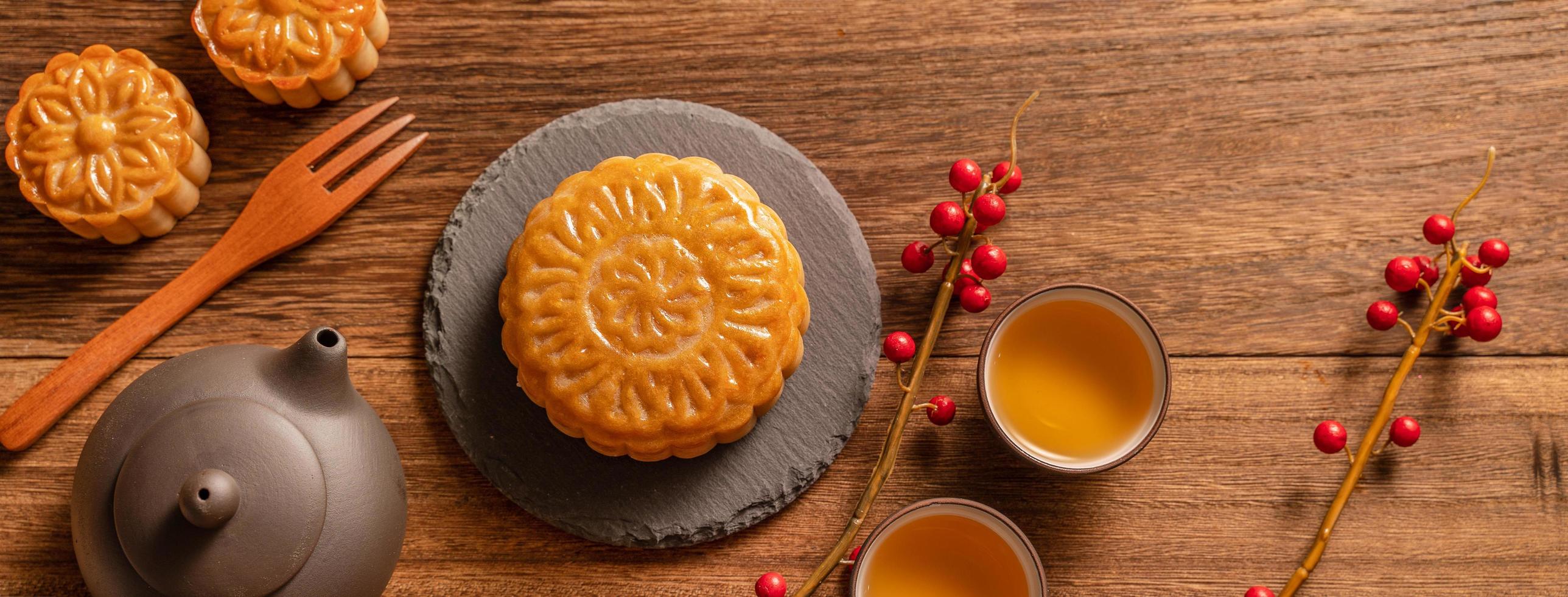 bolo de lua configuração de mesa de bolo de lua - pastelaria tradicional chinesa com xícaras de chá em fundo de madeira, conceito de festival de meio outono, vista superior, configuração plana. foto