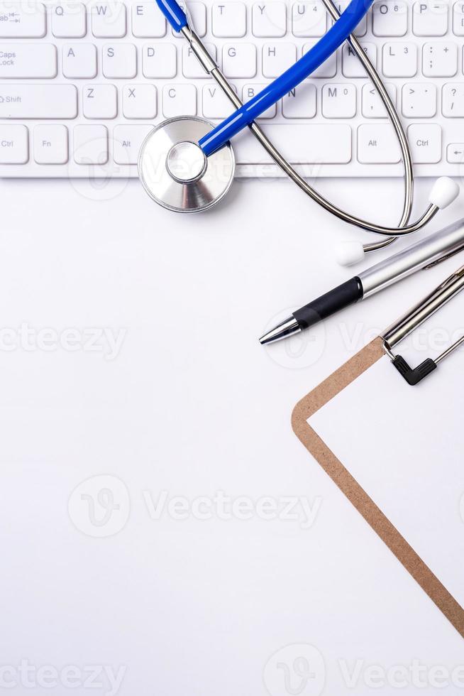 estetoscópio no teclado do computador em fundo branco. médico escreve caso médico conceito de tratamento de cuidados de longo prazo, vista superior, configuração plana, espaço de cópia foto