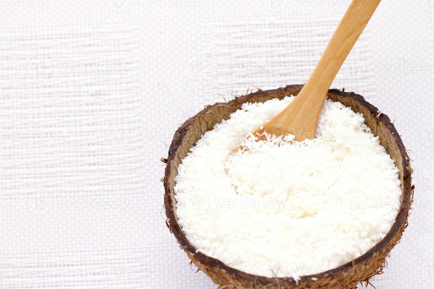 flocos de coco em casca de coco e colher de pau, ingredientes naturais foto