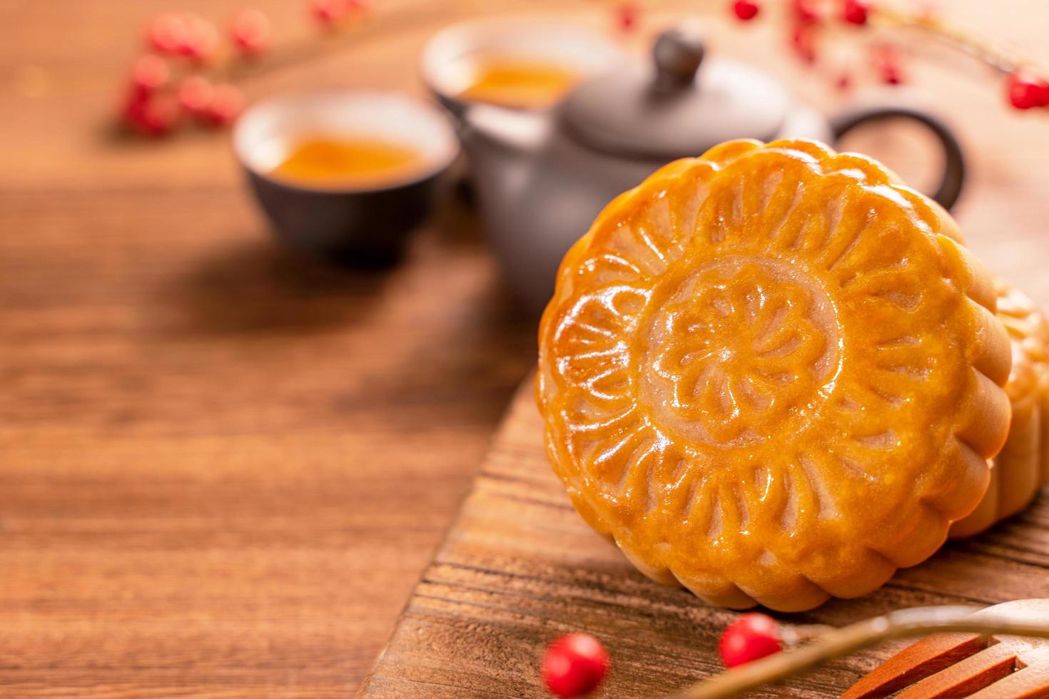 bolo de lua configuração de mesa de bolo de lua - pastelaria tradicional chinesa em forma redonda com xícaras de chá em fundo de madeira, conceito de festival de meio-outono, close-up. foto