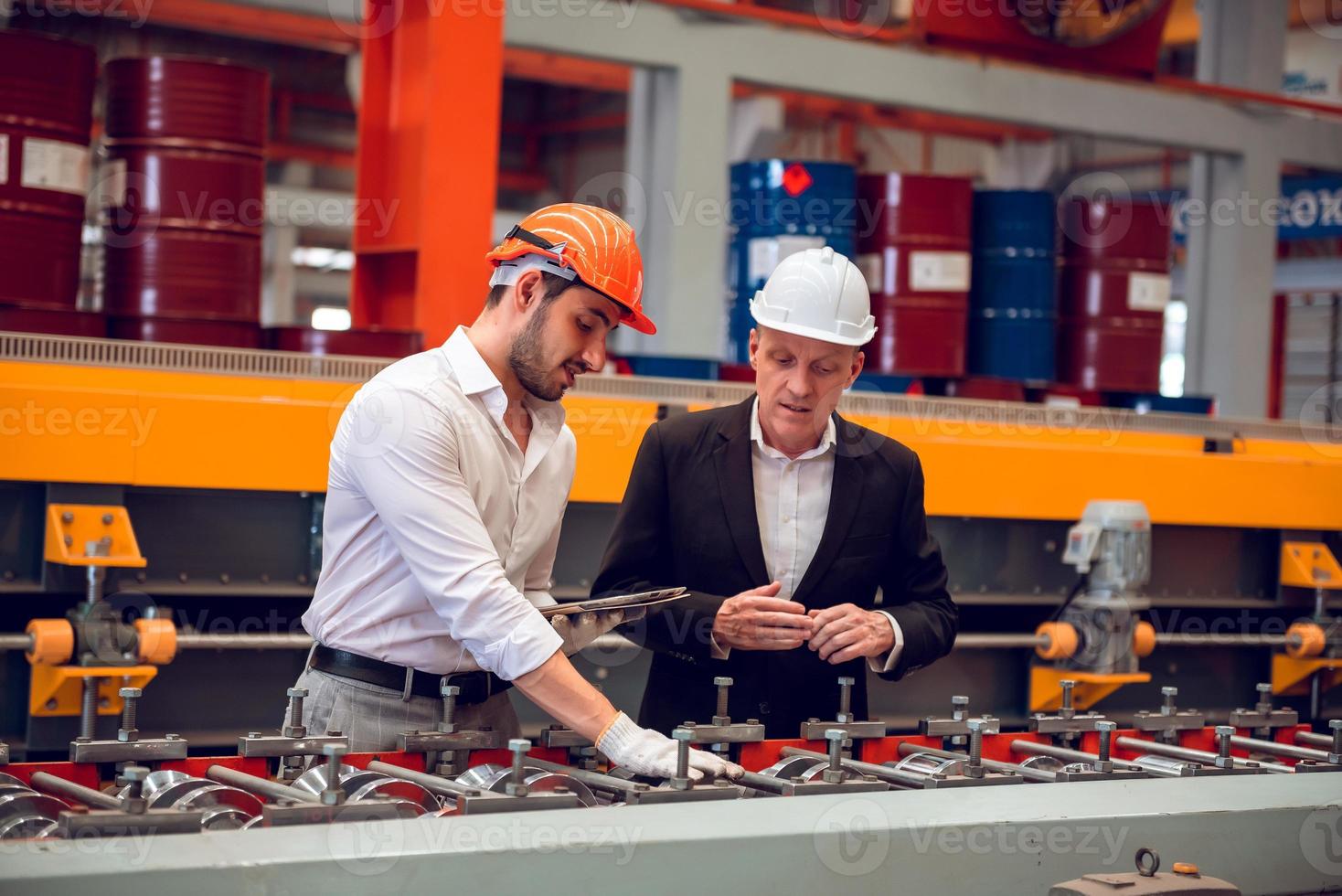 capataz operário e gerente de engenharia trabalhando juntos no local de trabalho industrial, usando capacete para segurança foto