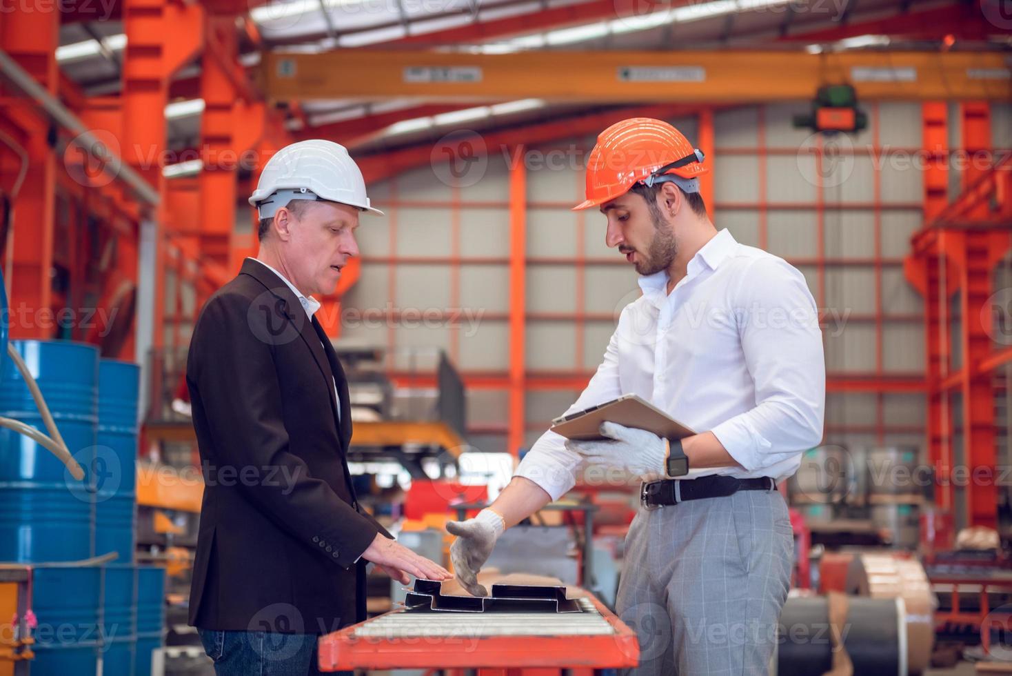 capataz operário e gerente de engenharia trabalhando juntos no local de trabalho industrial, usando capacete para segurança foto