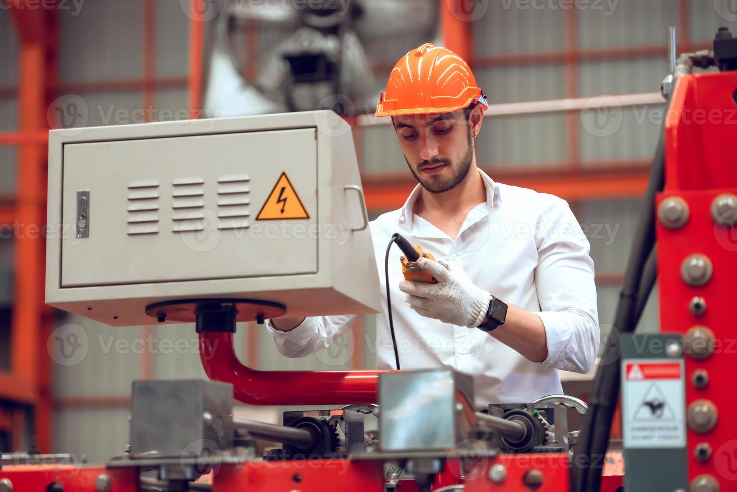 operário verificando o processo de máquina elétrica no local de trabalho industrial, usando capacete para segurança foto