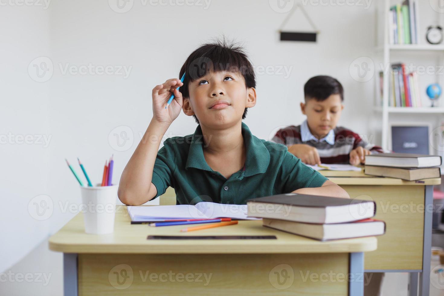 menino de escola primária confuso ao fazer exames em sala de aula foto