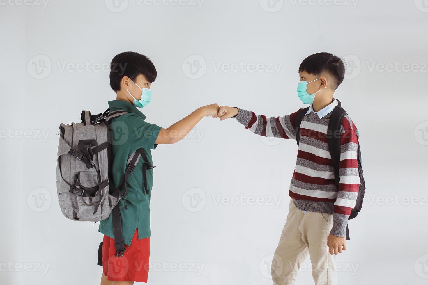 dois estudantes com máscara médica fazendo socos na prevenção do vírus corona foto