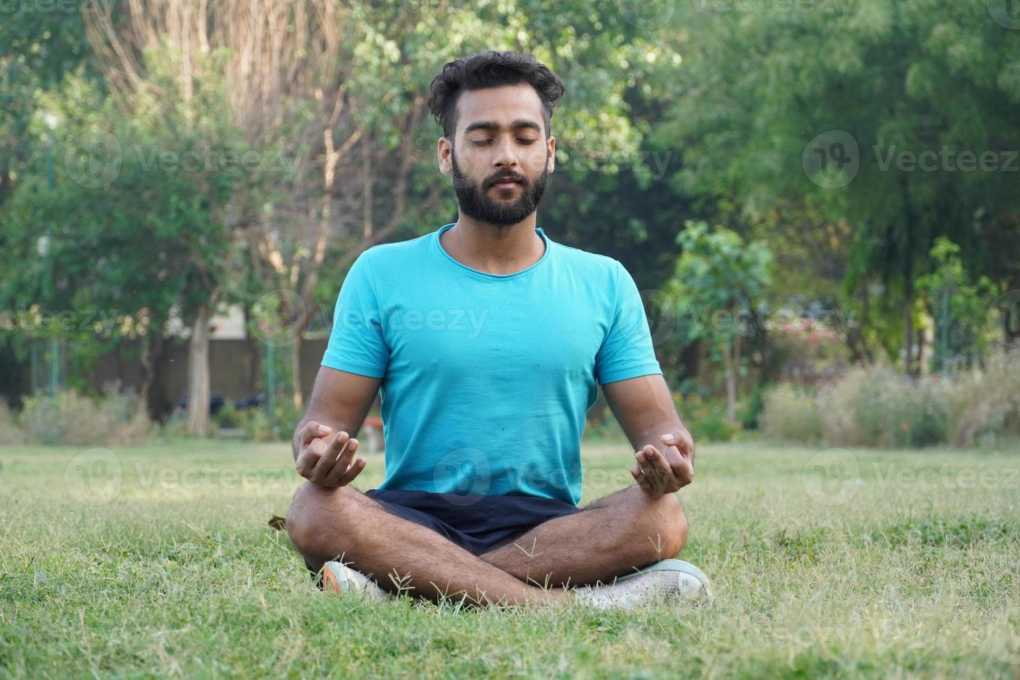 homem asiático atraente sentado em posição de meditação pose yoga pranayama equilíbrio na bela vista do parque durante o pôr do sol. conceito de saúde e bem-estar e fitness foto