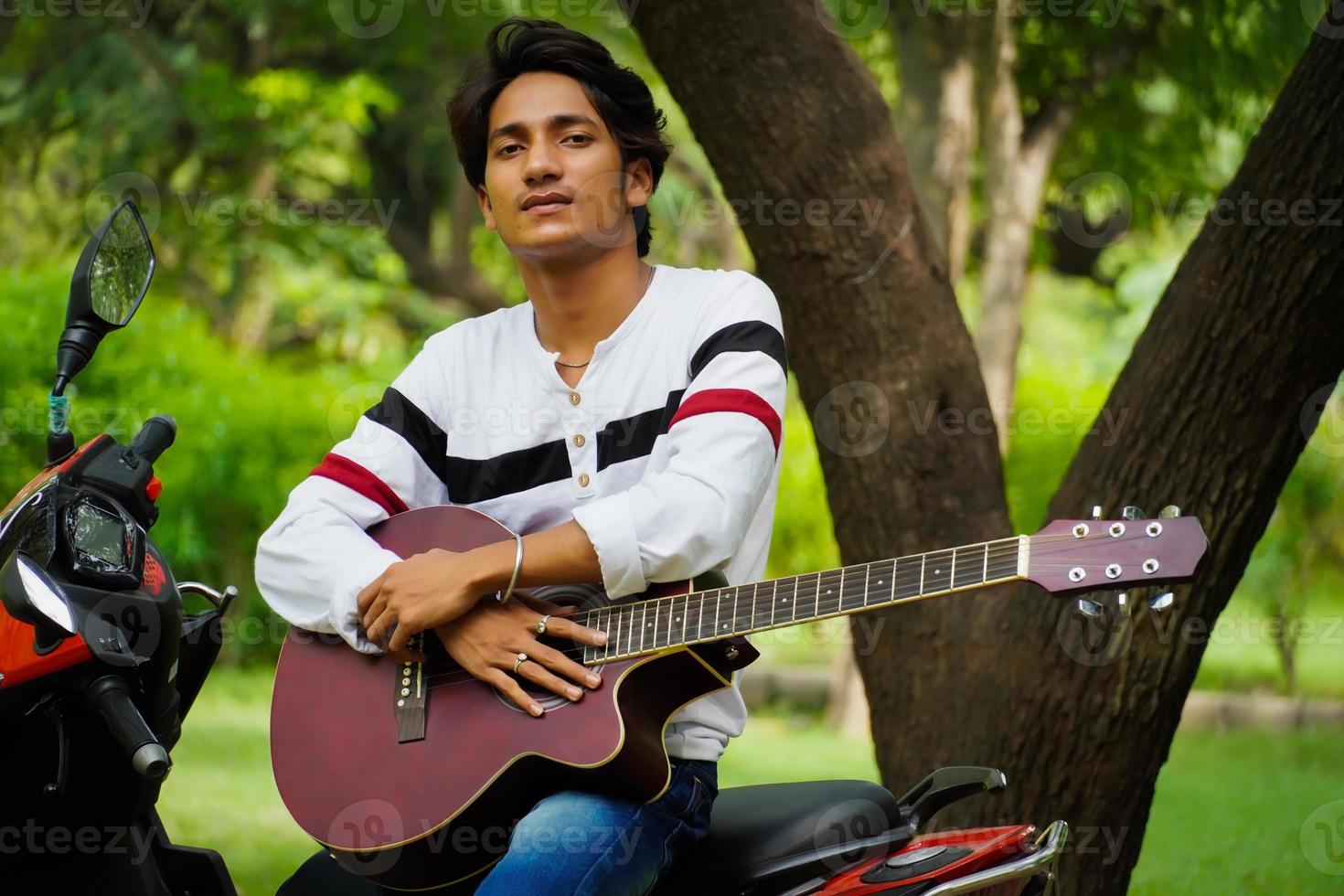 menino com guitarra vermelha com biike vermelho foto