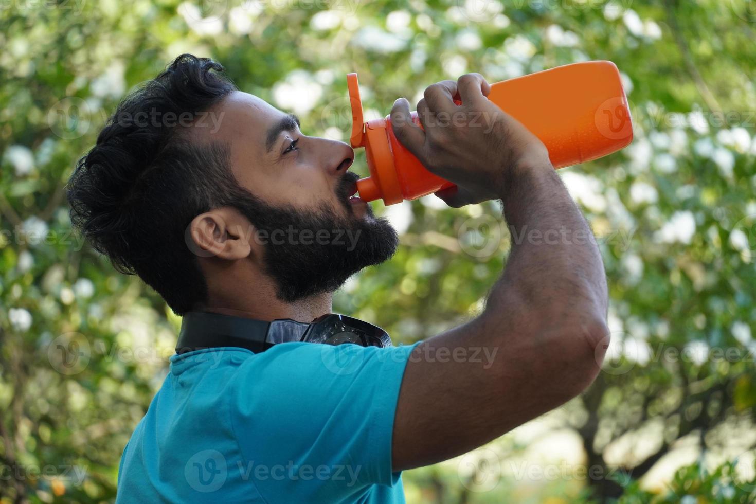 homem saudável com bebida de proteína em shaker no parque de manhã foto