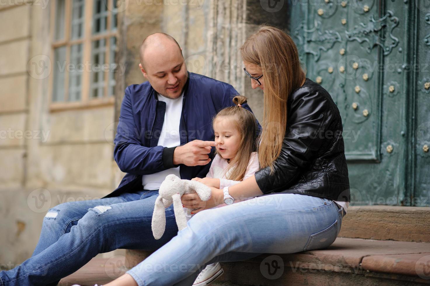 pais e sua filha estão sentados nos degraus de uma antiga igreja. foto