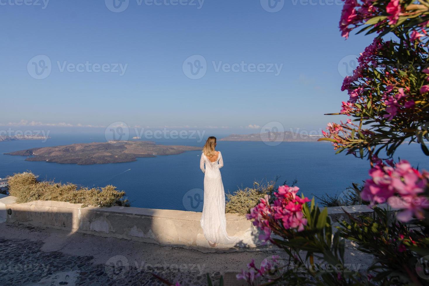 noiva linda em um vestido branco posando no contexto do mar mediterrâneo em thira, santorini. foto