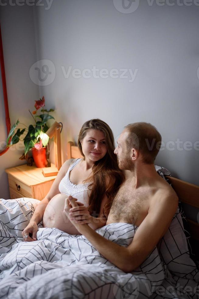casal grávido durante a quarentena se diverte na cama. foto