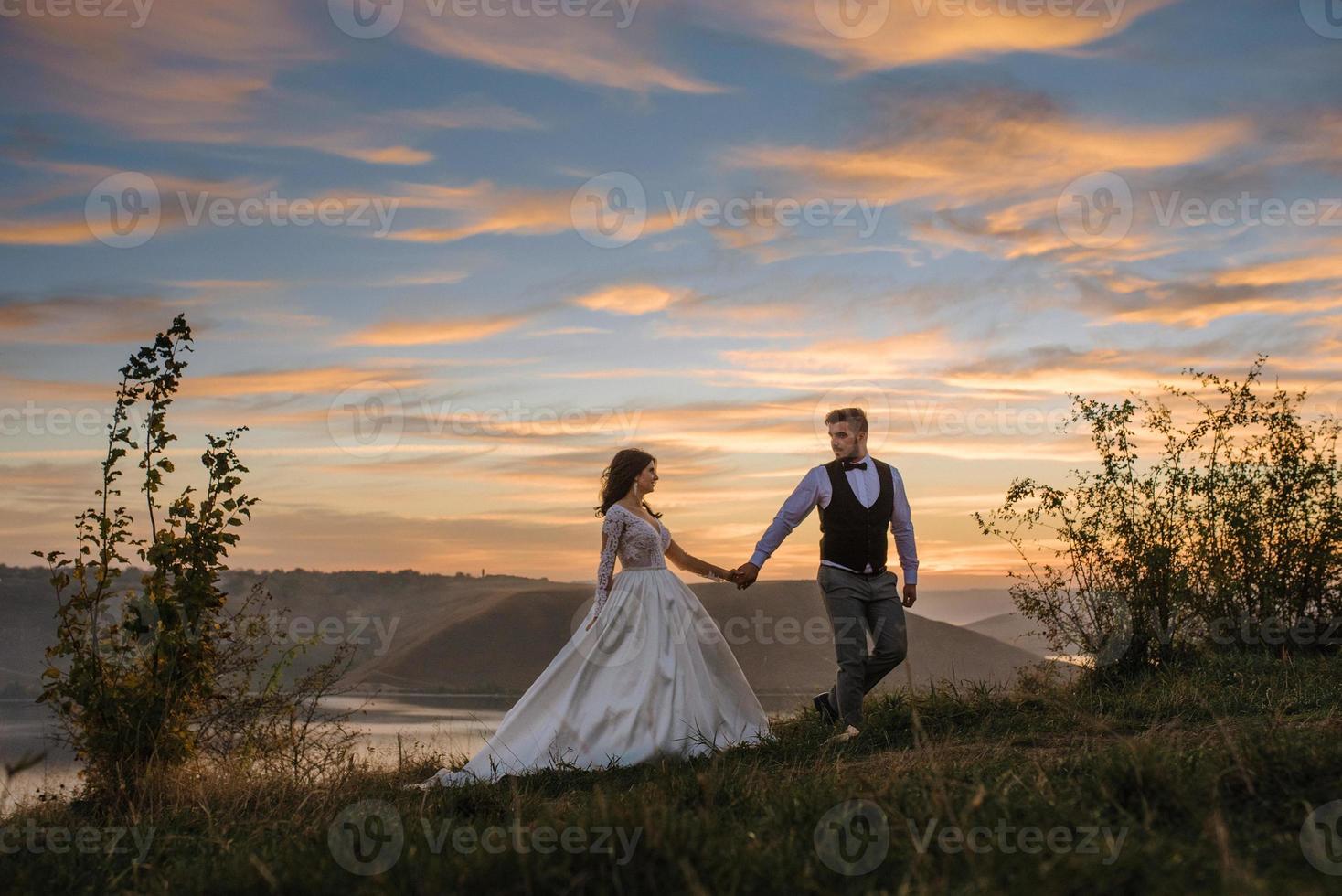 a noiva e o noivo estão andando perto do antigo castelo. o casal fica de costas um para o outro. foto