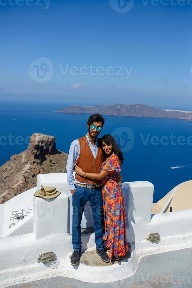 um homem e uma mulher estão se abraçando contra o pano de fundo do rock skaros na ilha de santorini. a aldeia de Imerovigli. foto