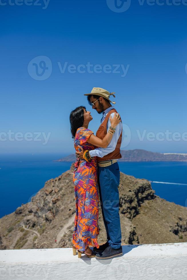 um homem e uma mulher estão se abraçando contra o pano de fundo do rock skaros na ilha de santorini. a aldeia de Imerovigli. foto