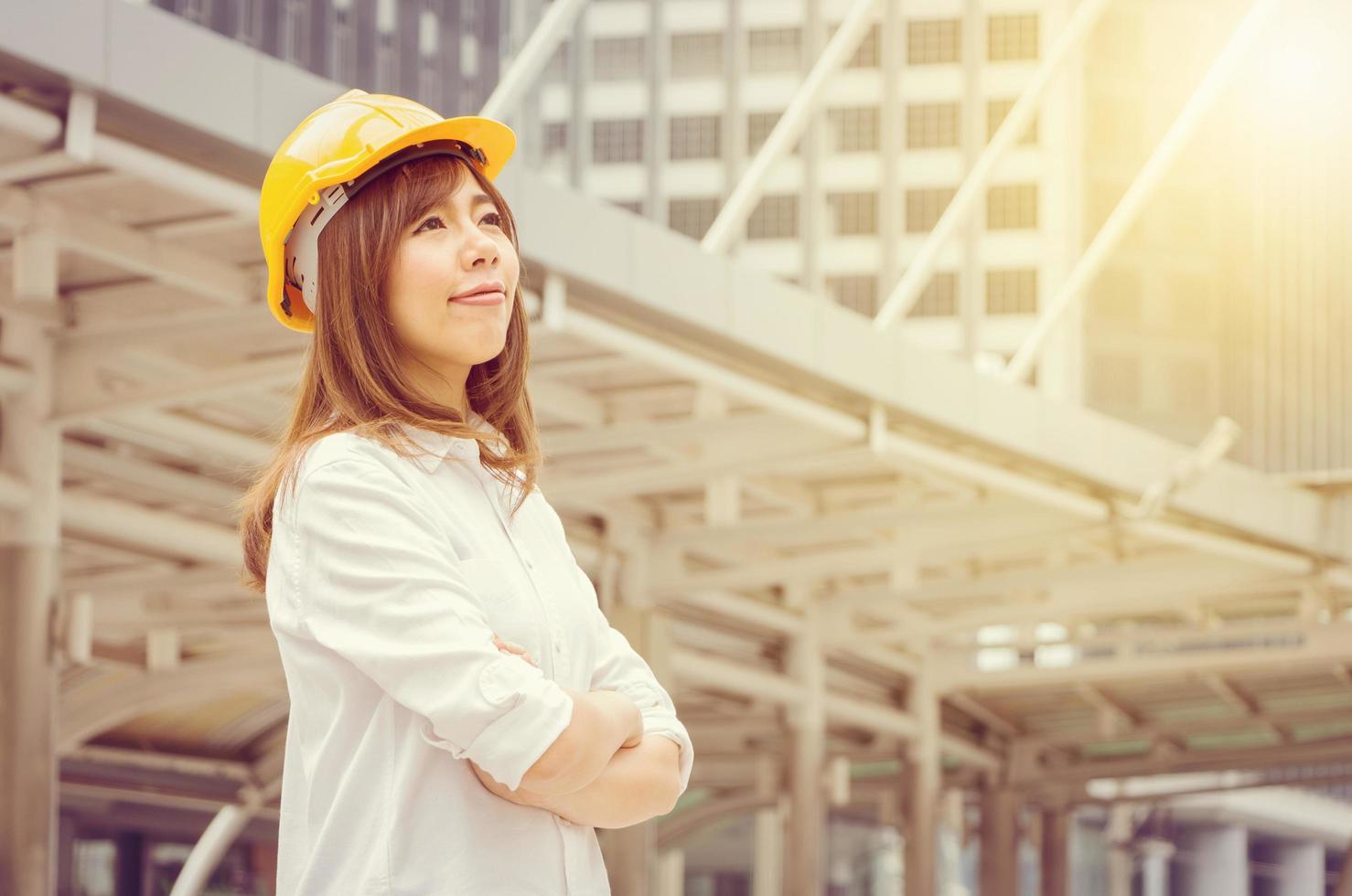 construção e manutenção pensam grande conceito, arquiteta feminina no capacete amarelo com fundo da cidade foto