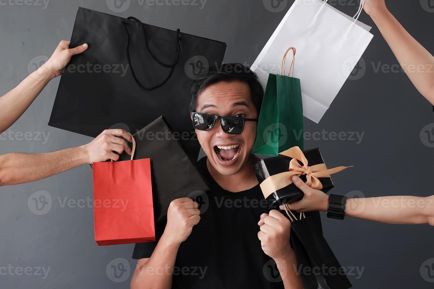 promoção de vendas de compras on-line engraçada com expressão boba homem viciado em compras por muitas mãos segurando sacolas de compras foto