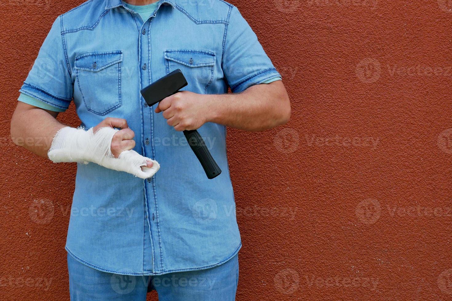 homens com mão engessada com um martelo foto