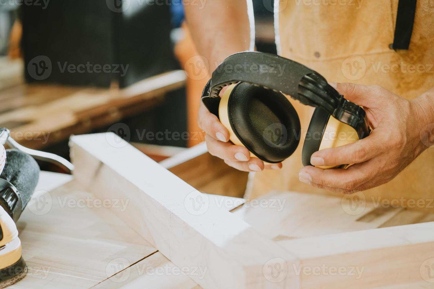 carpinteiro segurando protetores auriculares na oficina, fabricante de bricolage e conceito de marcenaria. foco seletivo foto