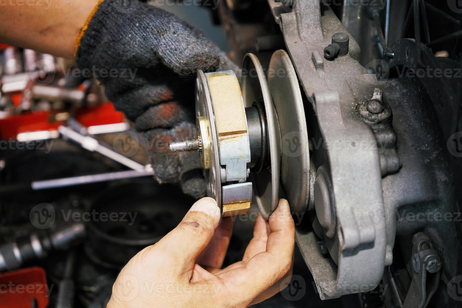 mecânico trabalhando instalando o sistema de embreagem na motocicleta scooter velha na garagem da motocicleta. substituição de embreagem e conceito de motocicleta de reparo e manutenção.foco seletivo foto