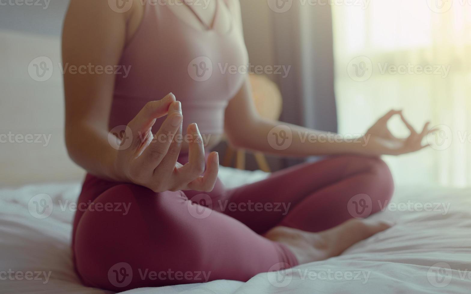 mão de close-up de mulher em sportsware pratica yoga pose de lótus para meditação em casa, mulher de bem-estar fazendo ioga para respiração e meditação confortável e relaxada. foto