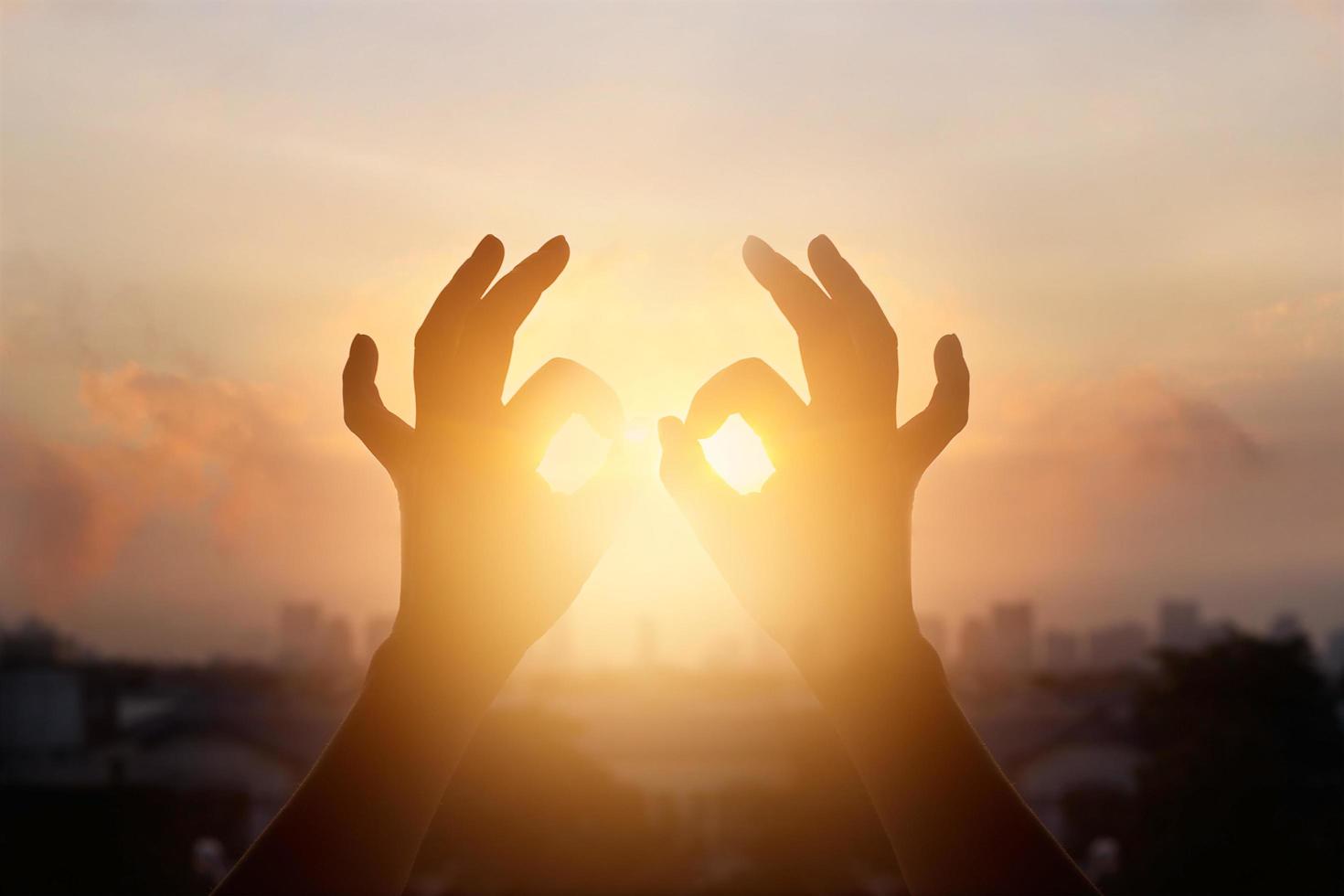 mãos de mulher em posição de lótus de ioga e meditação, silhueta no fundo do pôr do sol da natureza foto