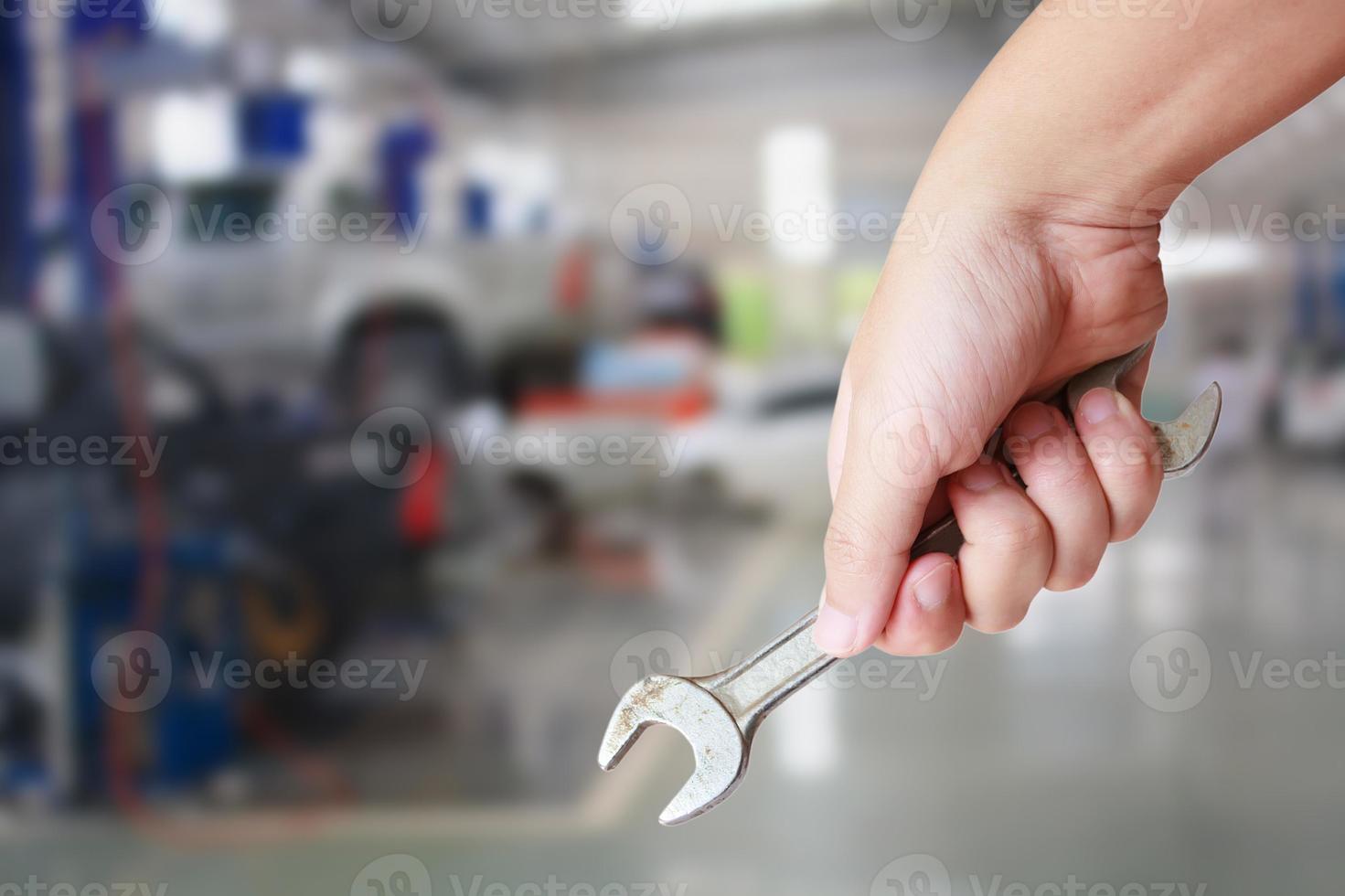 técnico segurando uma chave com fundo de centro de serviço de reparação de automóveis foto