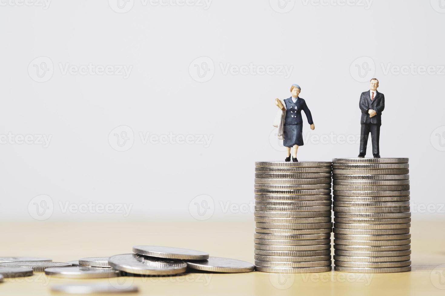 figura em miniatura do empresário de pé no empilhamento de moedas iguais de empresária para igualdade de gênero masculino e feminino do conceito de renda e salário. foto