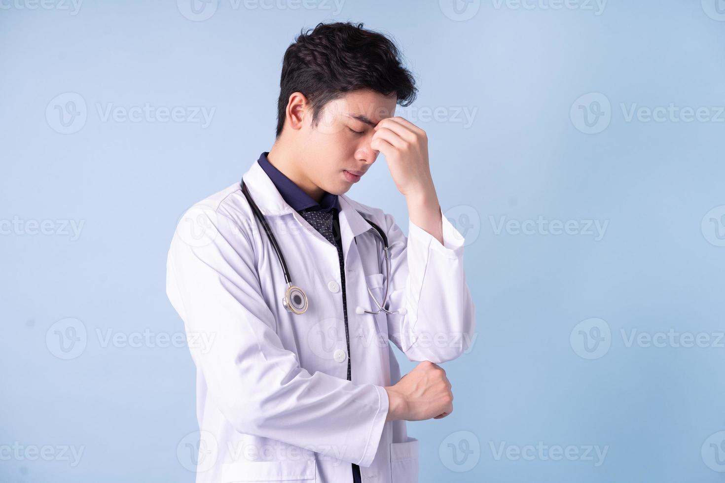 retrato de jovem médico masculino asiático sobre fundo azul foto