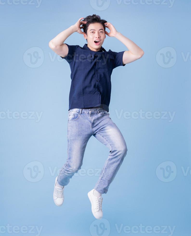 imagem de corpo inteiro de jovem asiático posando em fundo azul foto