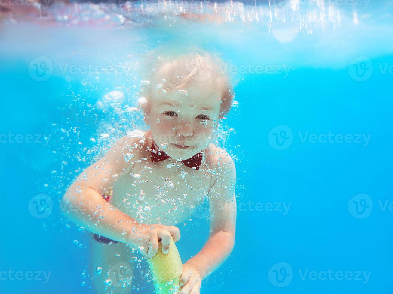 menino infantil com borboleta vermelha mergulhando debaixo d'água na piscina, aprenda a nadar. conceito de esporte e férias foto