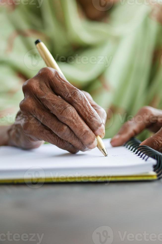 close-up da mão de mulheres sênior escrevendo no bloco de notas. foto