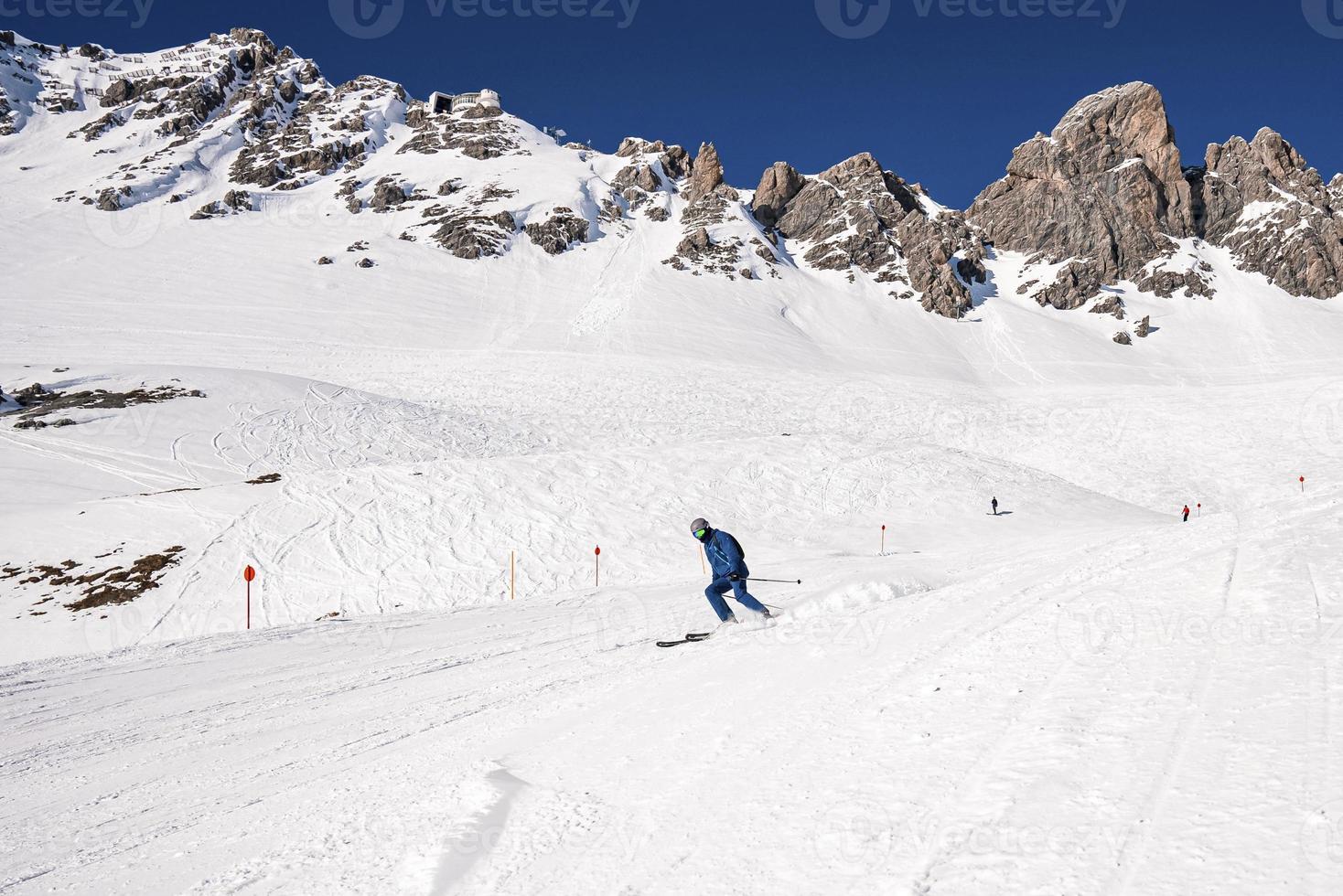 esquiador em roupas esportivas esquiando na paisagem de colina nevada contra a montanha foto