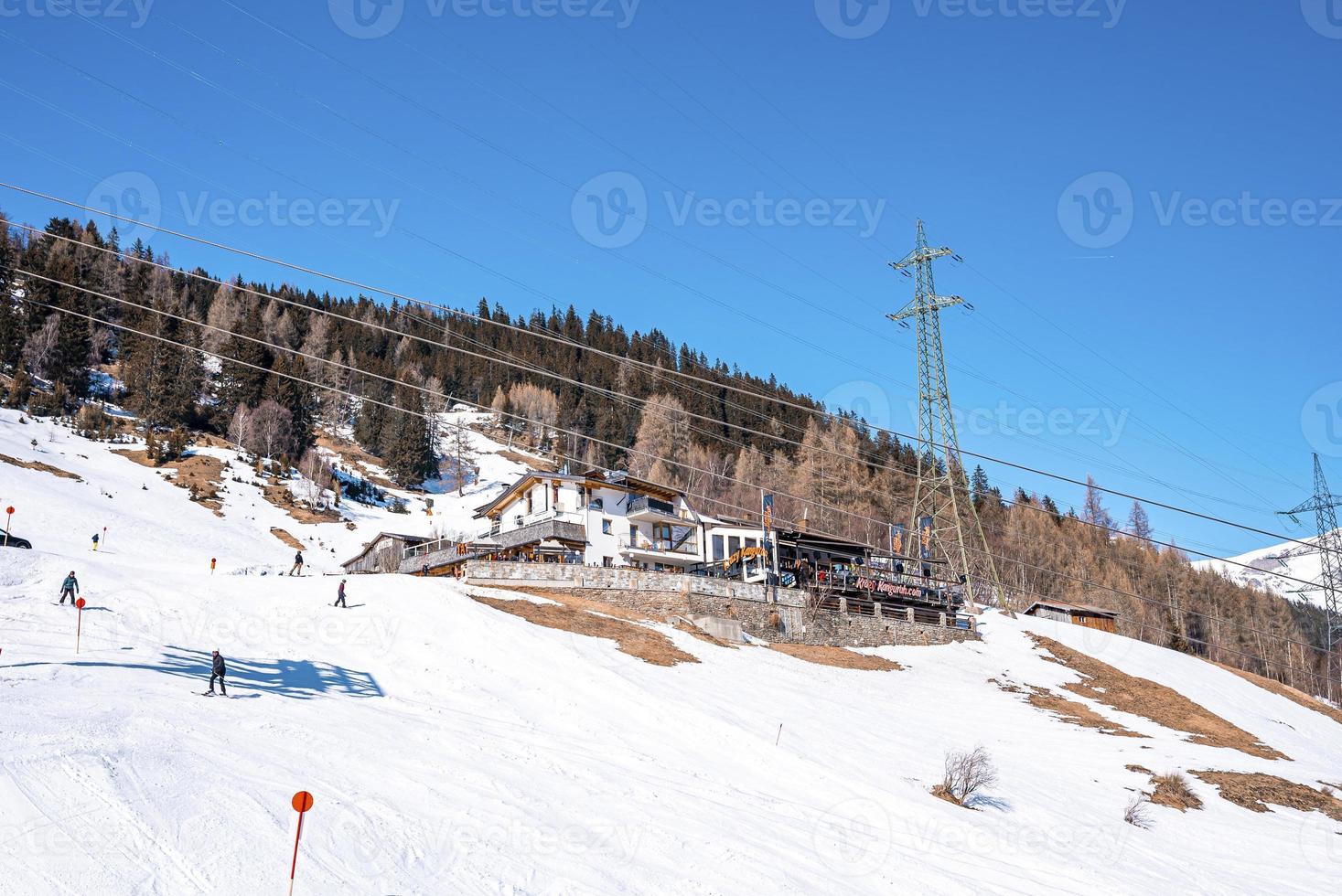 esquiadores esquiando pelo resort na encosta da montanha contra o céu nos Alpes foto