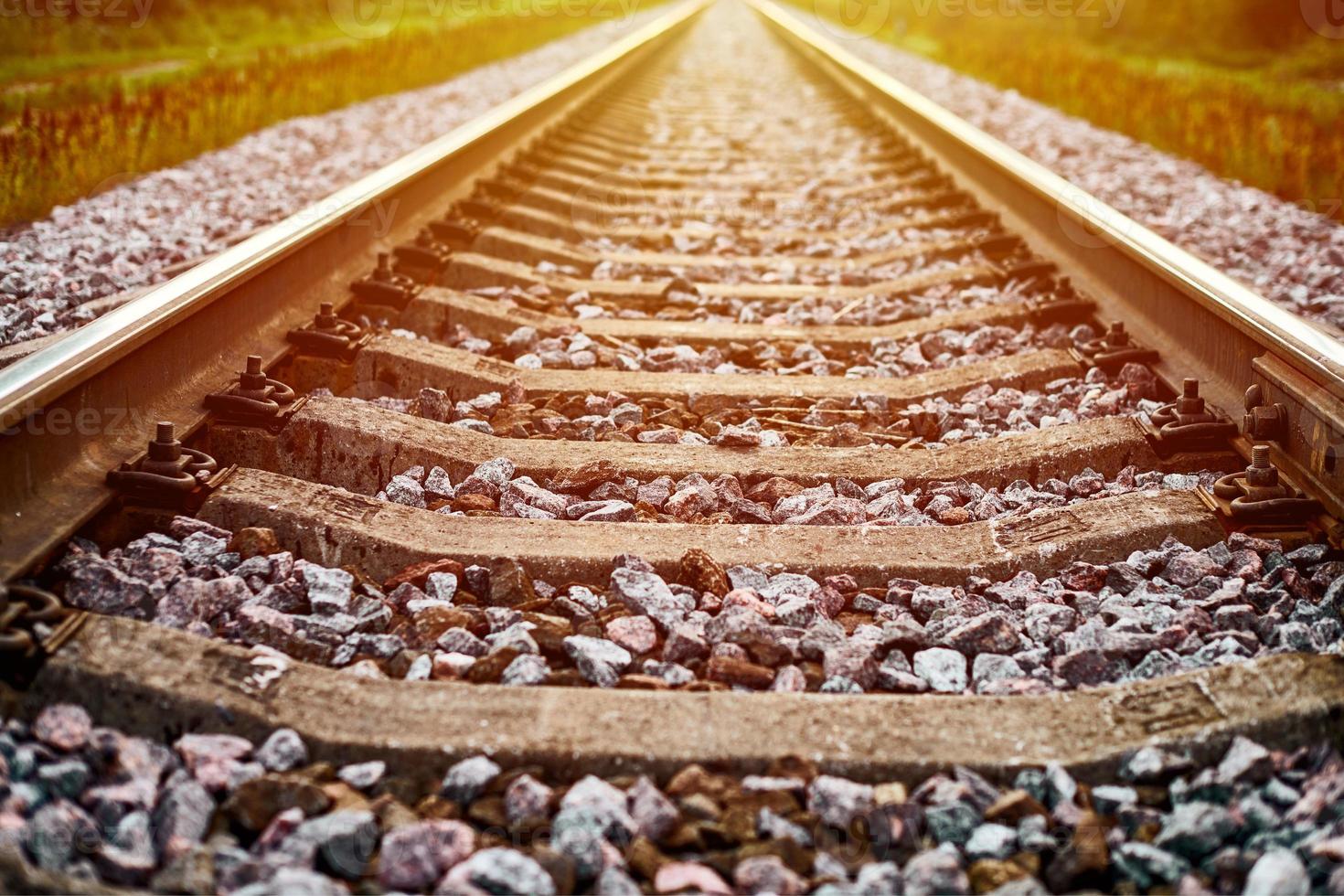 linha ferroviária à luz do sol, paisagem de trilho de trem ferroviário com cascalho de lastro e pedra britada foto