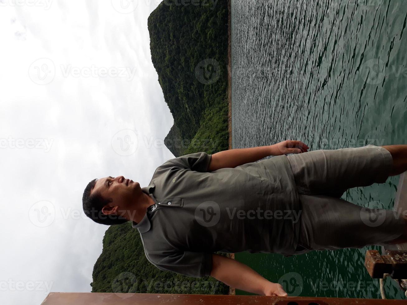 homens bonitos sentados no barco à procura de uma vista são viagens de conceito. homens da ásia viajando de barco olhando ao redor das montanhas sobre o belo lago. foto