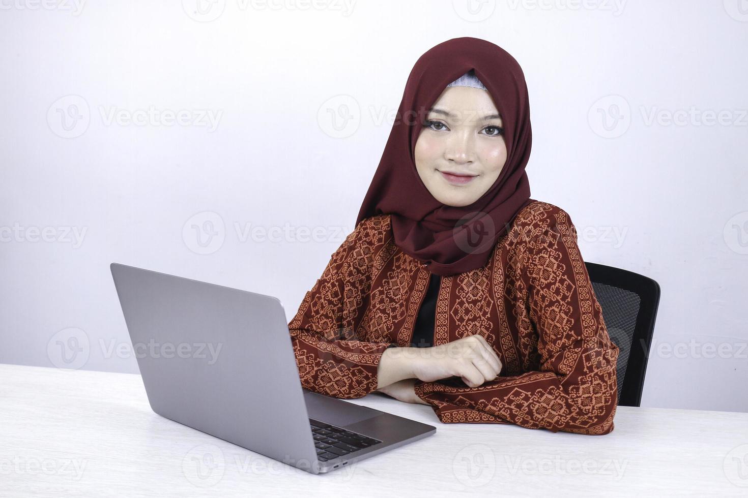 jovem islão asiático está sentado desfrutar e sorrindo ao trabalhar no laptop em fundo branco. foto