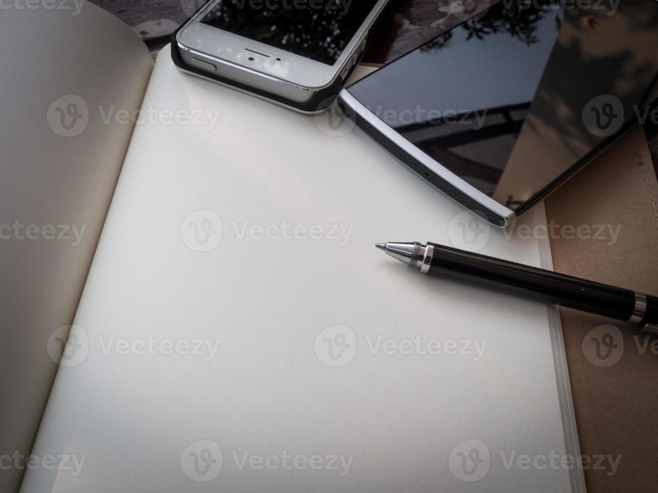 espaço de trabalho com óculos, caneta e smartphone, papel de nota e caderno na velha mesa de madeira foto