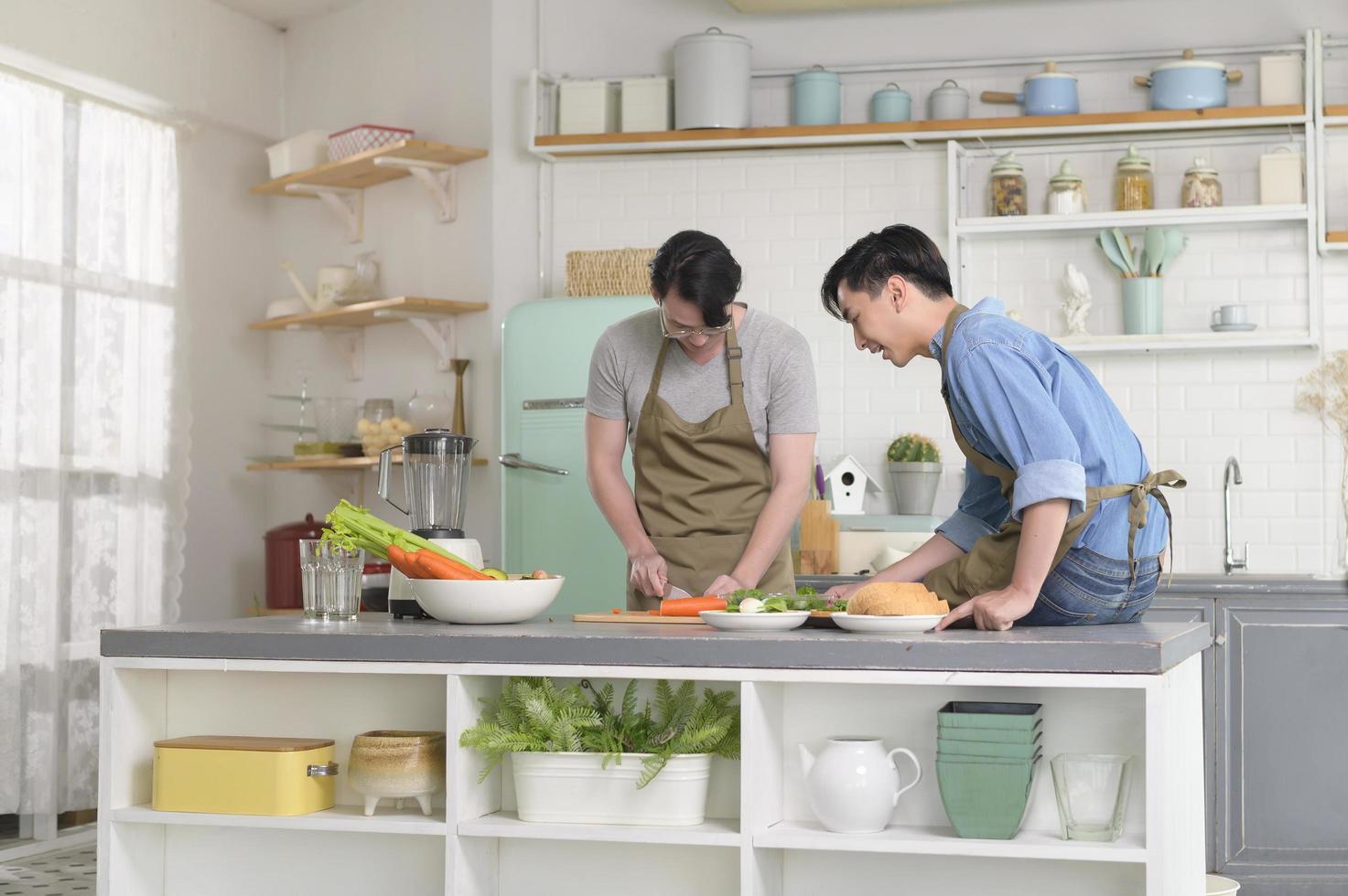 jovem casal gay sorridente cozinhando juntos na cozinha em casa, lgbtq e conceito de diversidade. foto