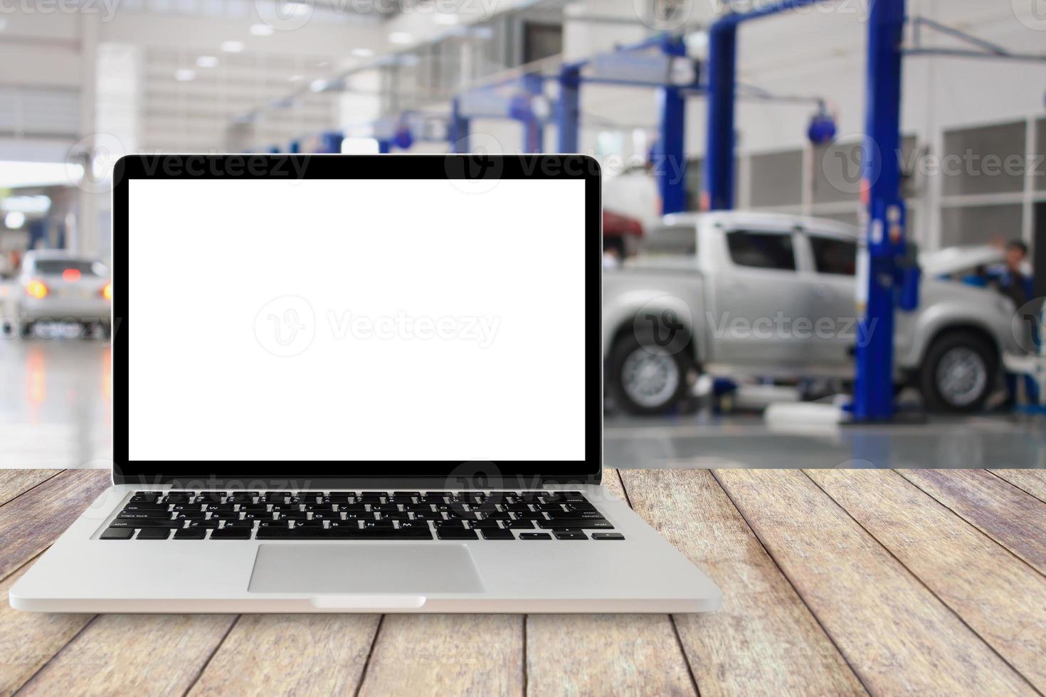 laptop na mesa de madeira com fundo de centro de serviço de carro turva foto