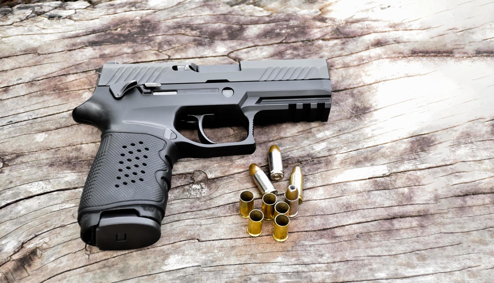 arma de pistola preta automática de 9 mm e balas na mesa de madeira. foto